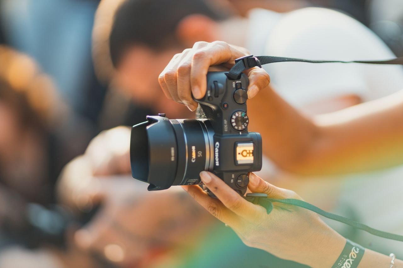 A detailed shot of a person holding a camera, capturing a moment outdoors.