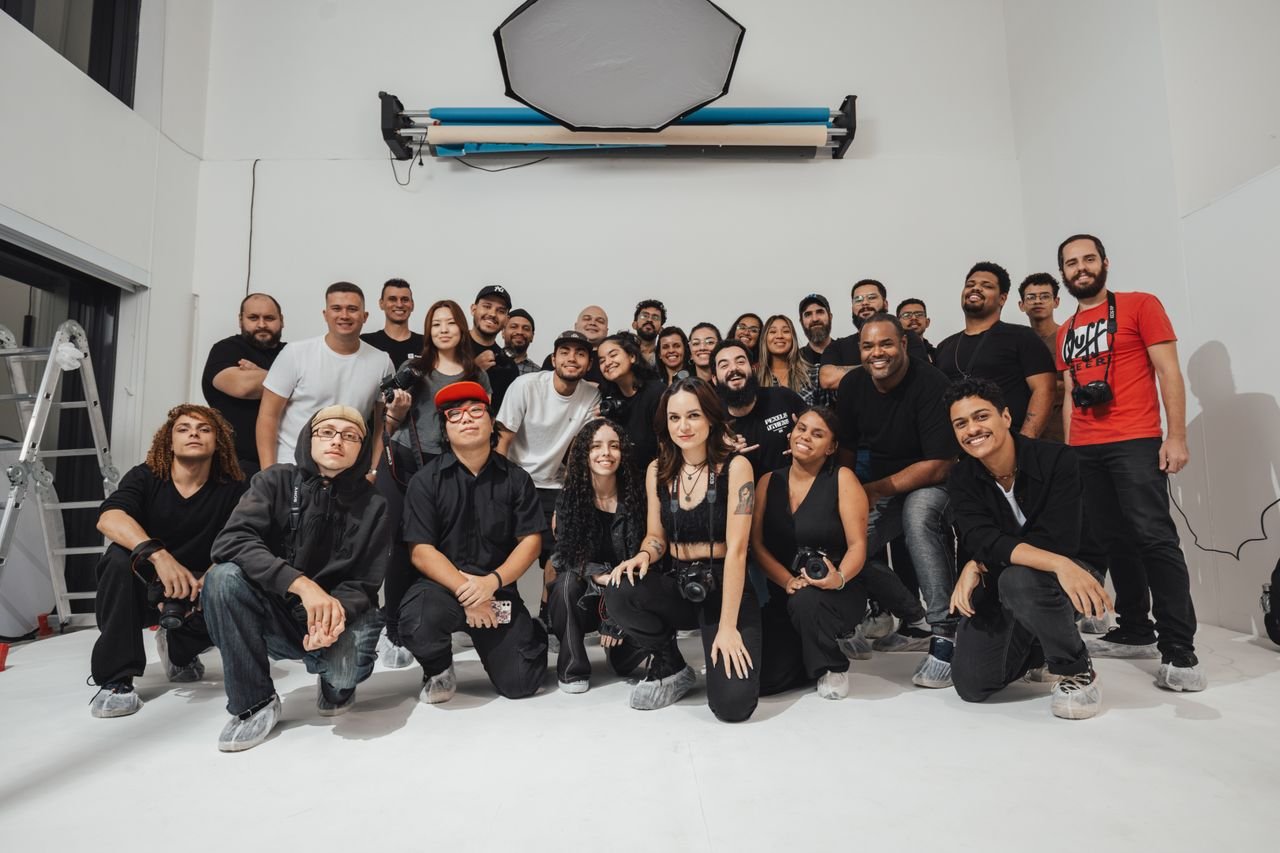 A large group of photographers gathered in a brightly lit photo studio, showcasing diversity and creativity.